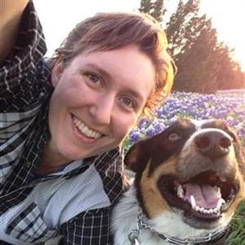 Alyson Holley, assistant director of bands, with one of her dogs in a field of bluebonnets 